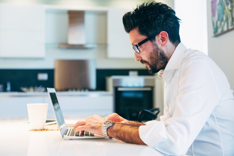 Man working on computer in kitchen
