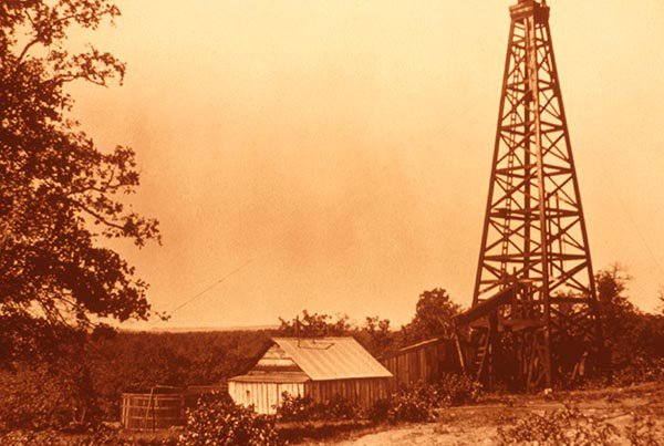 Sepia photo of pumpjack and drilling structure from 1920s